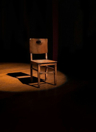 Einzelner Holzstuhl auf einer leeren Theaterbühne